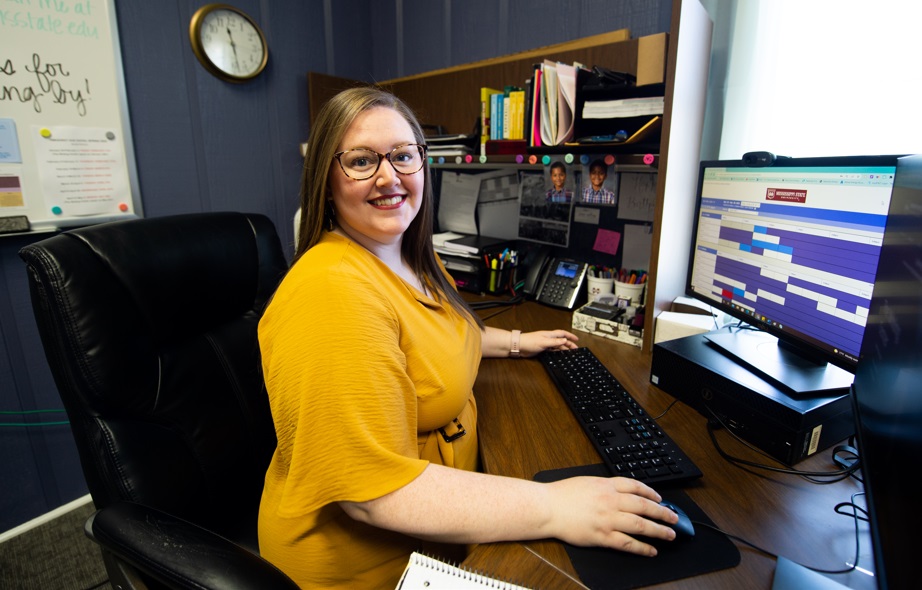 Administrator Sits at Desk Looking at Online Scheduler