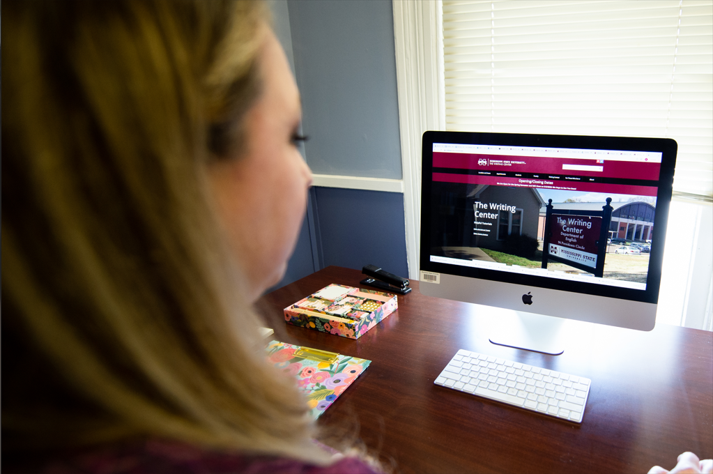 Woman at Desks Looks at the Writing Center Website